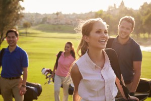 Group Of Golfers Walking Along Fairway Carrying Golf Bags