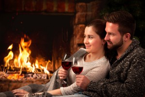 Couple relaxing with glass of wine at fireplace