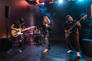 Handsome singer with rock and roll band performing music on stage