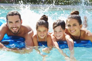 Portrait Of Family On Airbed In Swimming Pool