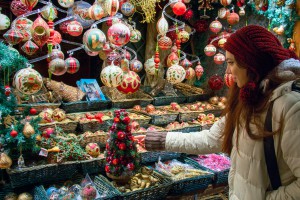 Shopping for Christmas Holidays, woman at market display window choosing Christmas tree decorations, balls and other seasonal art crafted products of modern, vintage and traditional styles