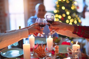 Beautiful family smiling happy and confident. Eating roasted turkey and toasting with cup of wine celebrating Christmas at home