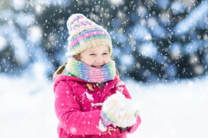 Child playing with snow in winter. Kids outdoors.